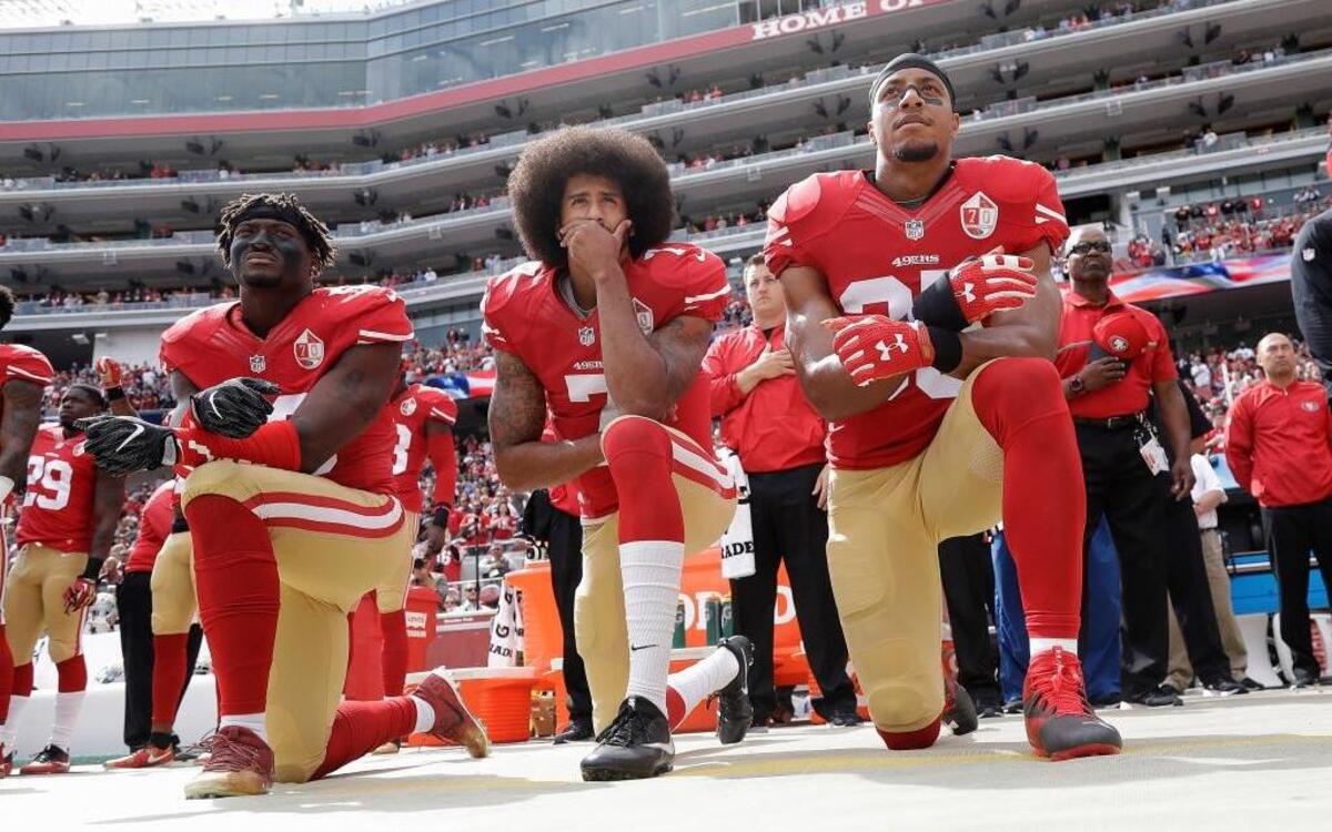 In this Oct. 2, 2016, file photo (from left), San Francisco 49ers outside linebacker Eli Harold, quarterback Colin Kaepernick and safety Eric Reid kneel during the national anthem before an NFL football game against the Dallas Cowboys in Santa Clara, Calif. What started as a protest against police brutality has mushroomed a year later into a divisive debate over the future of Kaepernick who refused to stand for the national anthem and now faces what his fans see as blackballing for speaking out in a country roiled by racial strife.