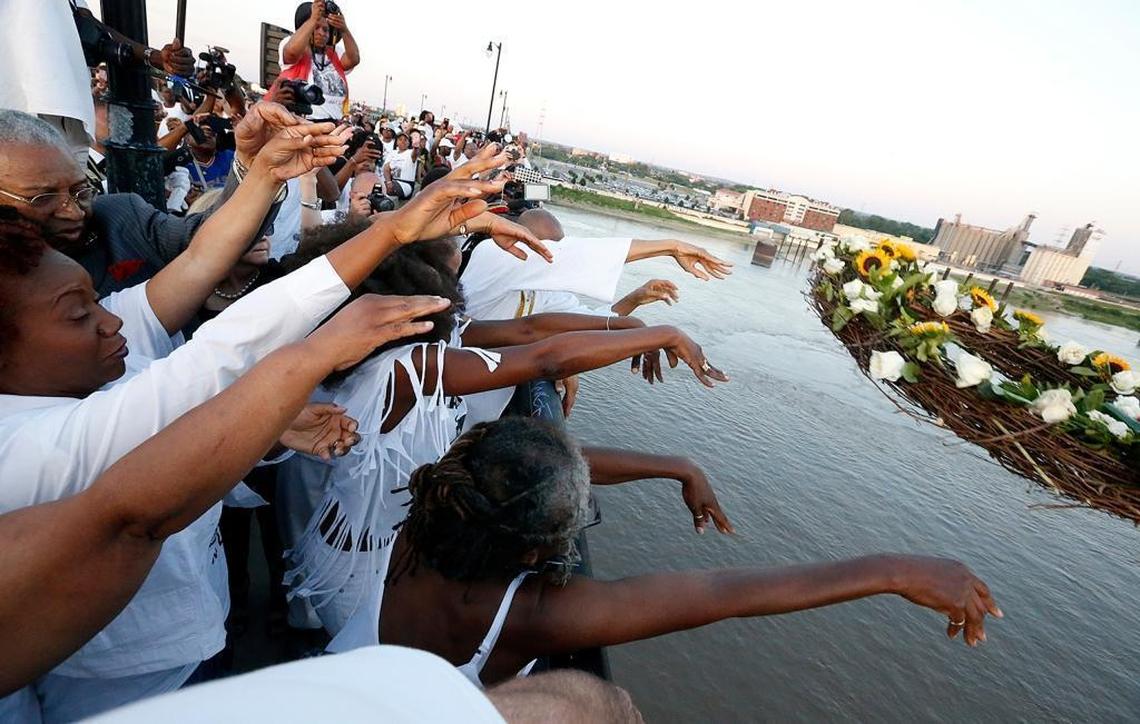 Participants in the Sunday remembrance of the 1917 race riots in East St. Louis throw a commemorative wreath from the Eads Bridge.
