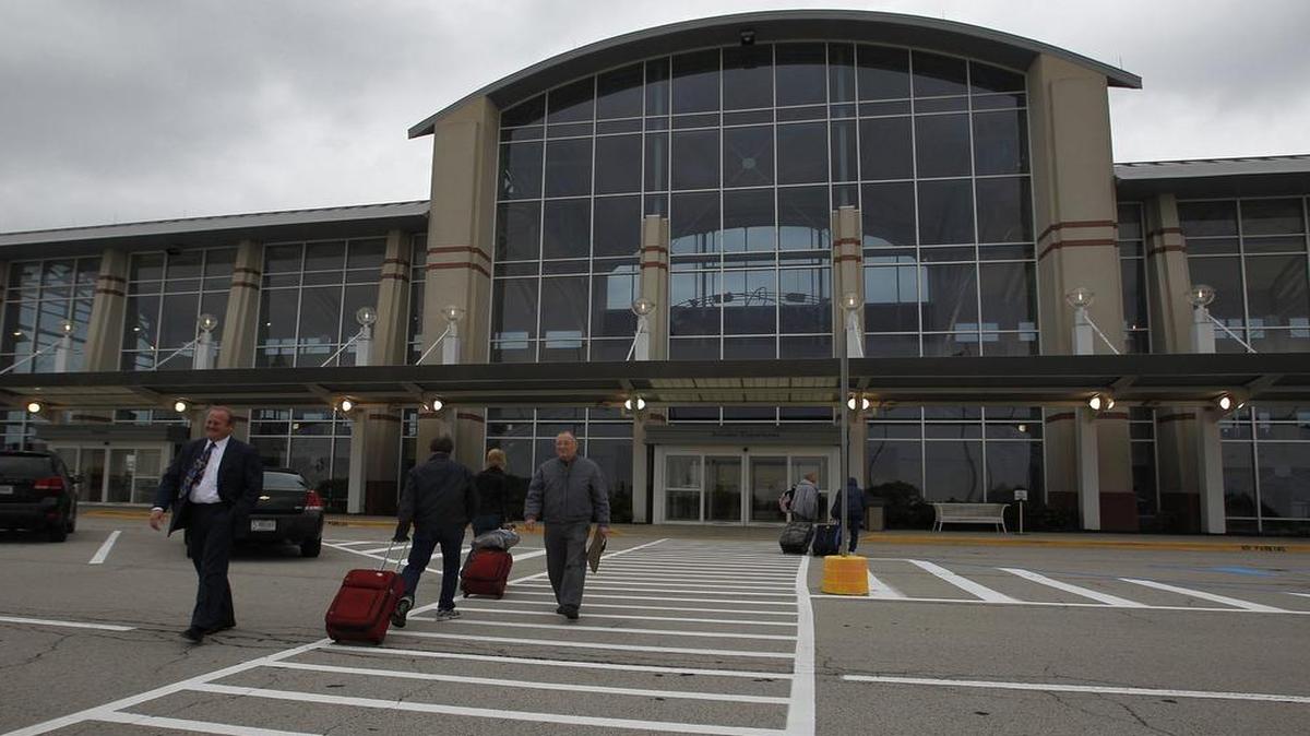 Passengers walk past St. Clair County Chairman Mark Kern as they head into MidAmerica Airport.