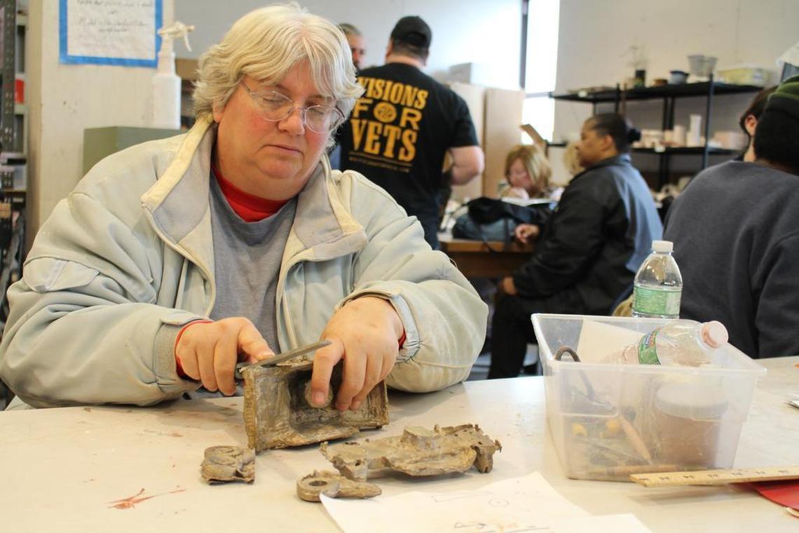 Veteran Marj Santhuff, of St. Louis, uses a metal file to smooth out rough edges on a bronze statue of a military Humvee in the sculpture studio of Fontbonne University as part of the Visions for Vets art program.