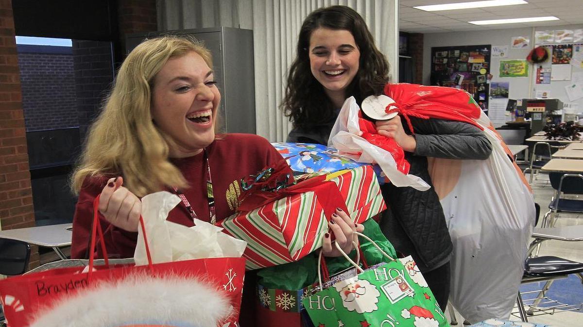 Members of Belleville East's Octagon Club wrapped presents before school on Thursday for families they have adopted this year. Here, club vice-president Molly Korte (left) and president Sophia Fike carry wrapped gifts to a teacher's room for storage. Molly is 18 and is a senior at East. Sophia is 17, and also a senior. Both live in Belleville.