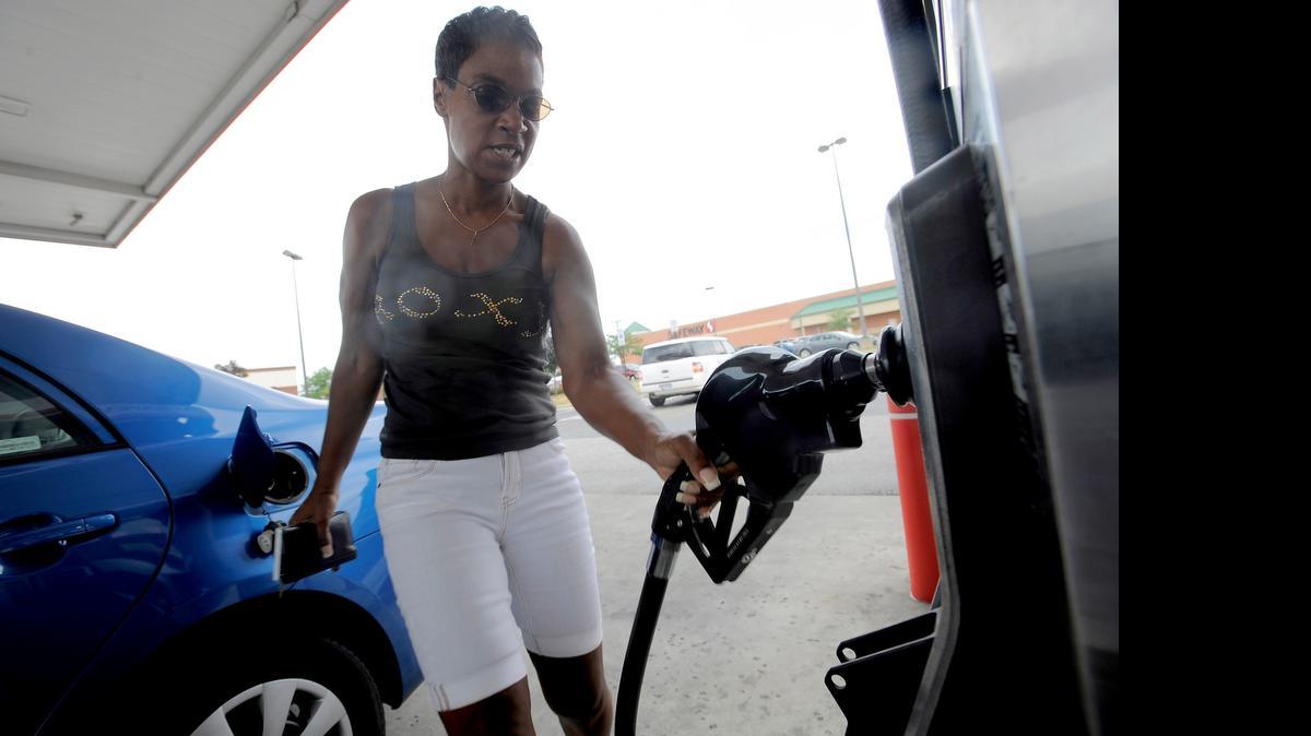 
A driver finishes pumping gas at a station in Baltimore. Experts are predicting lower gas prices this summer, compared to 2014.
