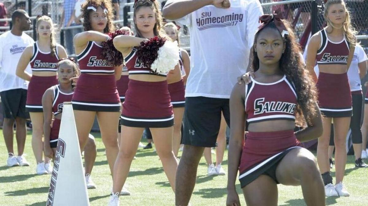 SIU cheerleaders Alaysia Brandy (right) and Czarina Tinker kneel during the national anthem prior to the Salukis’ game against Illinois State at Saluki Stadium on Saturday, Sept. 30.