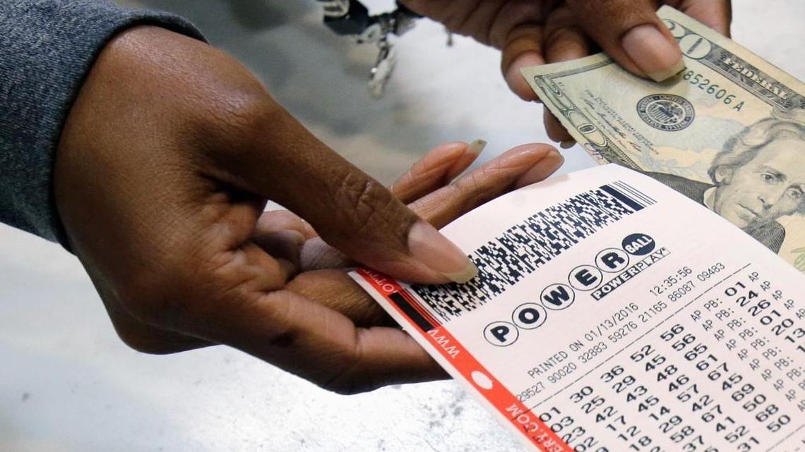 In this file photo, a clerk hands over a Powerball ticket for cash.