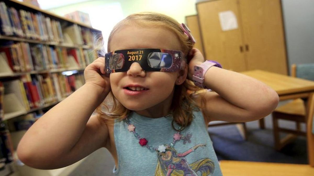 Emmalyn Johnson, 3, tries on her free pair of eclipse glasses at Mauney Memorial Library in Kings Mountain, N.C.