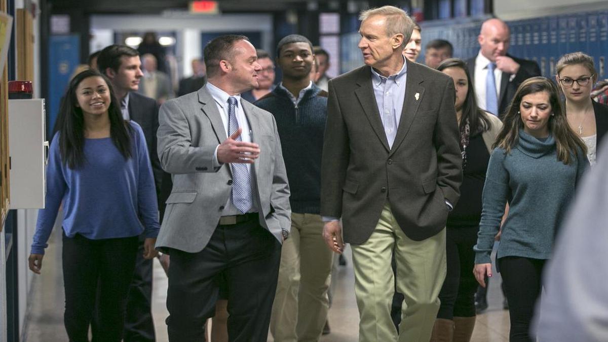 Belleville East principal Jason Karstens speaks with Illinois Gov. Bruce Rauner as they tour the campus with students during Rauner's visit Thursday at Belleville East High School. Rauner spoke to students about school funding.