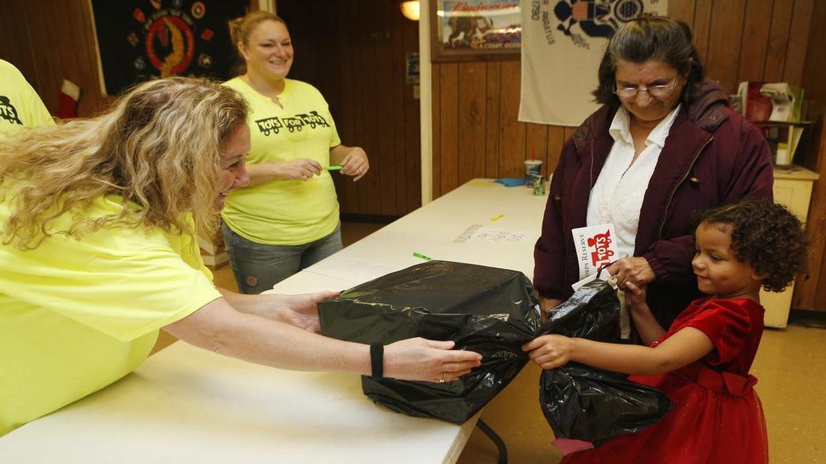 Alicai Parker, 4, gets a Christmas gift from volunteer Lisa Miller during the Toys for Tots event at the VFW in O'Fallon on Saturday. Also pictured is her grandmother Helen Parker.