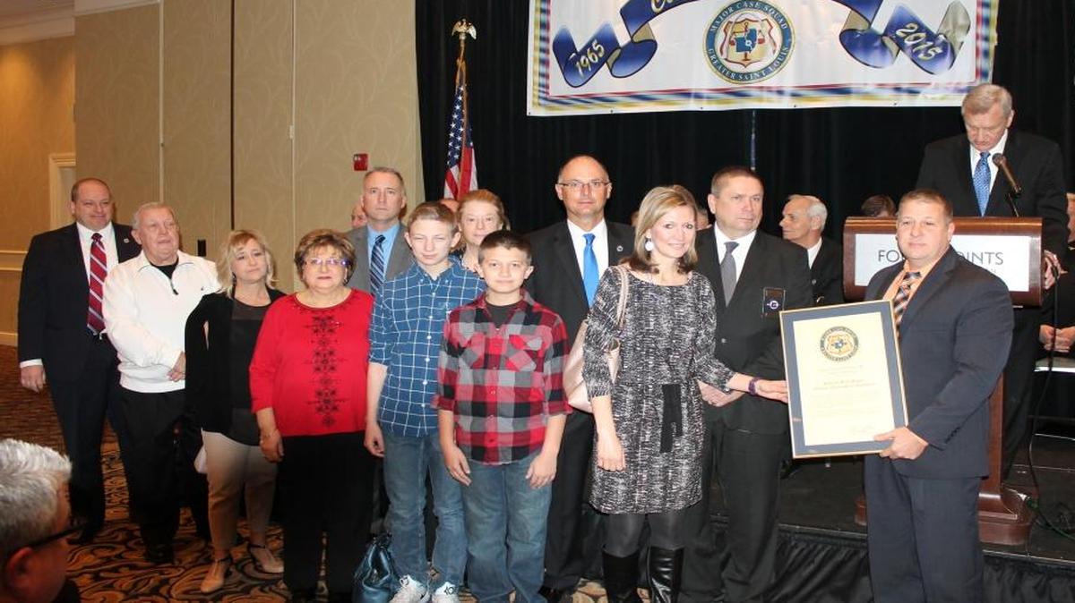 Pictured are (left to right front row): Chief Eric Van Hook, Larry Riggar, Denise Arendall, Dolly Riggar, Geno and Brice, Kami Riggar, Officer Brian Riggar; (back row) Florissant, Mo. Police Department Major Tim Fagan, St. Louis County Police Captain Terry Barton, Captain Jim Cavins, Florissant, Mo. Police Chief Tim Lowery.