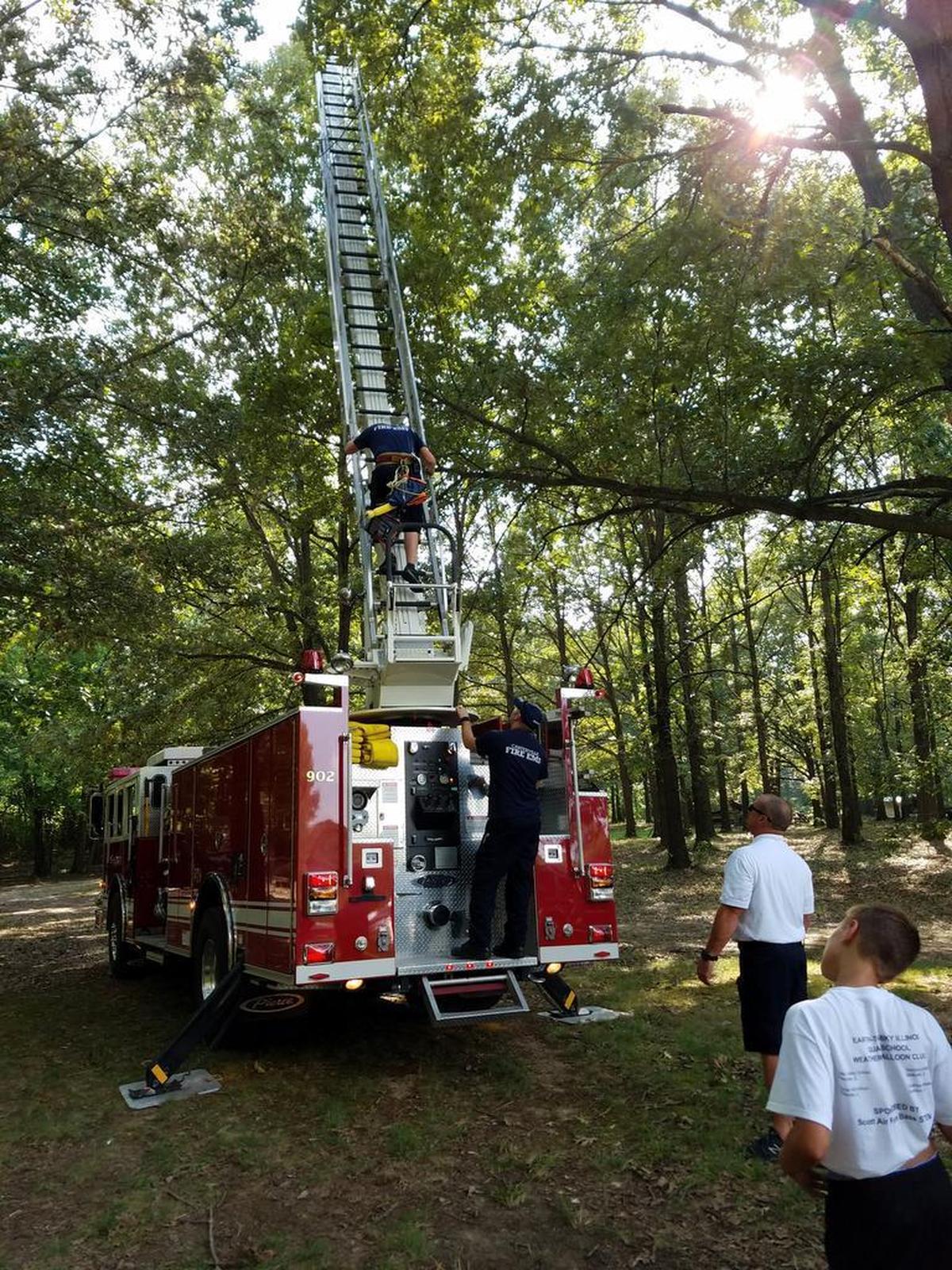 The Carterville Fire Department helps the Balloonatics, a junior high science club from the metro-east, retrieve a weather balloon from a tall oak tree 90 minutes after they launched it from Saluki Stadium in Carbondale.