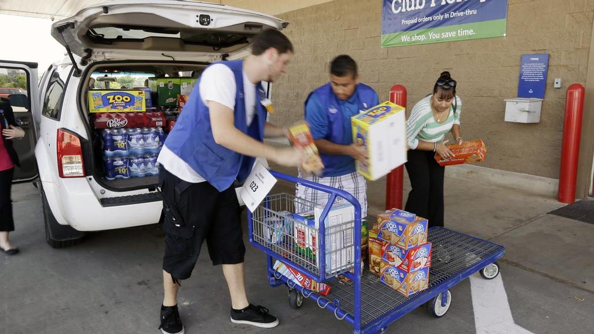 In this June 4, 2015, photo, a Sam’s Club customer, right, and store workers load previously ordered merchandise into a van at a pickup location at the Bentonville, Ark., store.