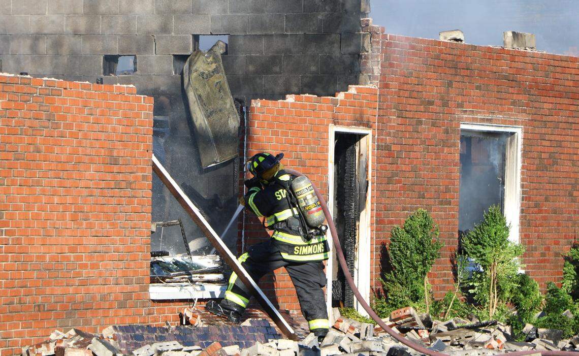 An area firefighter douses flames at a three-alarm fire on the 5600 block of Forest Avenue in Washington Park Tuesday. The building, which houses many of the city’s municipal departments, partially collapsed during the fire.