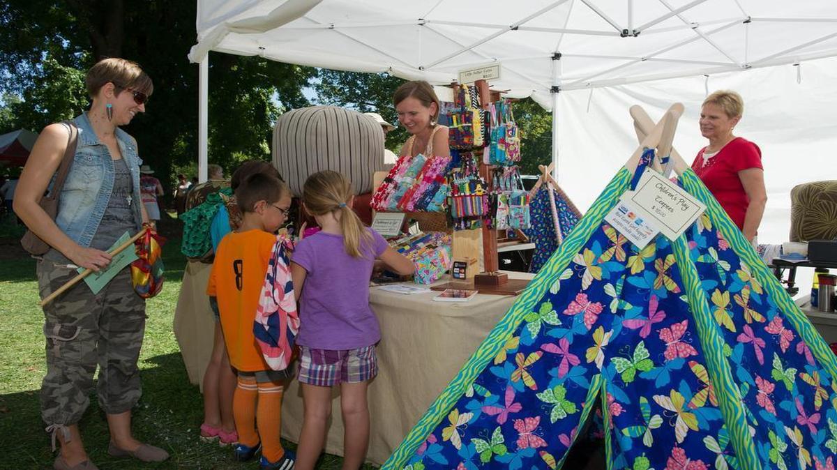 
A family looks at some of the crafts for sale at a booth during the 2014 Strange Folk Festival. 
