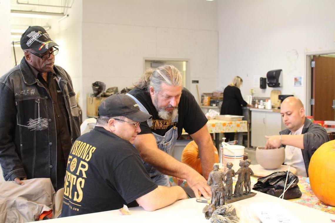 Sculptor Scott Beaty, center, talks to veteran Brad Martin about his bronze statues as Del Marion looks on and John Zuniga works on a vase in the sculpture studio of Fontbonne University as part of the Visions for Vets art program.