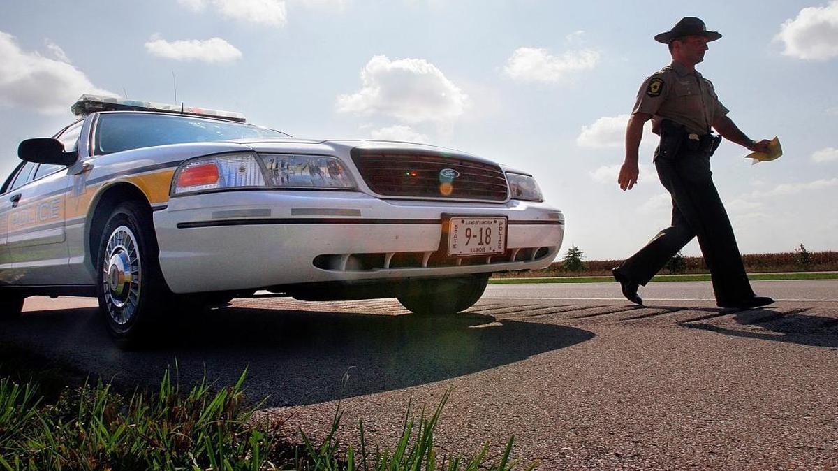 In this Sept. 15, 2006, file photo, Illinois State Police Officer Sgt. Mike Vorreyer walks from his patrol car to issue a ticket for speeding to a driver on Interstate 72 near Jacksonville. While the state’s sinking fiscal condition has forced belt tightening throughout the state capital in the past two years, the Illinois State Police has spent nearly $8 million to put 300 new vehicles on the road and not a penny of it from tax dollars.