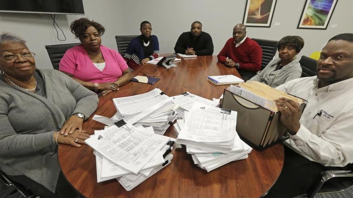 In this Thursday, Jan. 28, 2016 photo, Frankie Redditt, President/CEO of Ashley’s Quality Care, Inc., left, and Michael Robinson, CFO, are joined by other officers at the company headquarters with stacks of invoices to the state and payroll bills on the table in Chicago. As Illinois politicians continue to squabble over a budget that should have taken effect July 1, hundreds of state contractors have been left with little more than I.O.U.s, according to more than 500 pages of documents, since Nov. 1, released to The Associated Press under the Illinois Freedom of Information Act. The state owes $2 million to Ashley’s Quality Care in Chicago, according to Robinson.