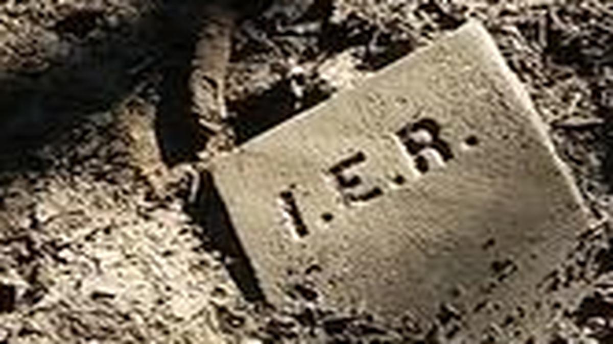 A tiny grave marker with only initials lies flat in a tire track from a logging truck at the old St. George Cemetery near Centreville.