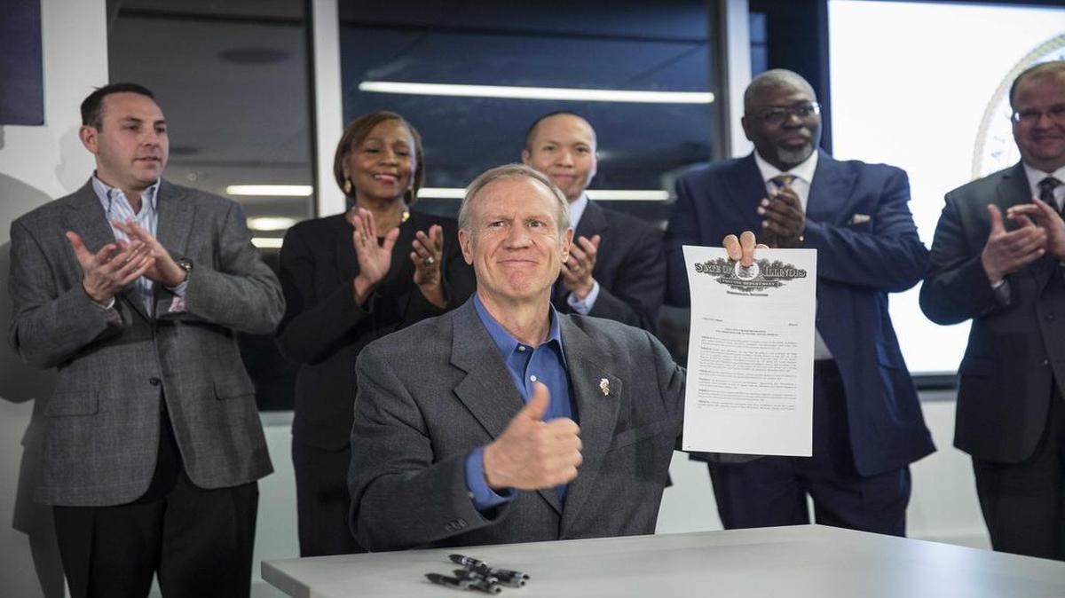 Illinois Gov. Bruce Rauner on Wednesday in Chicago holds up an executive order he just signed that will create a privately run and funded economic development agency that he says will create jobs.