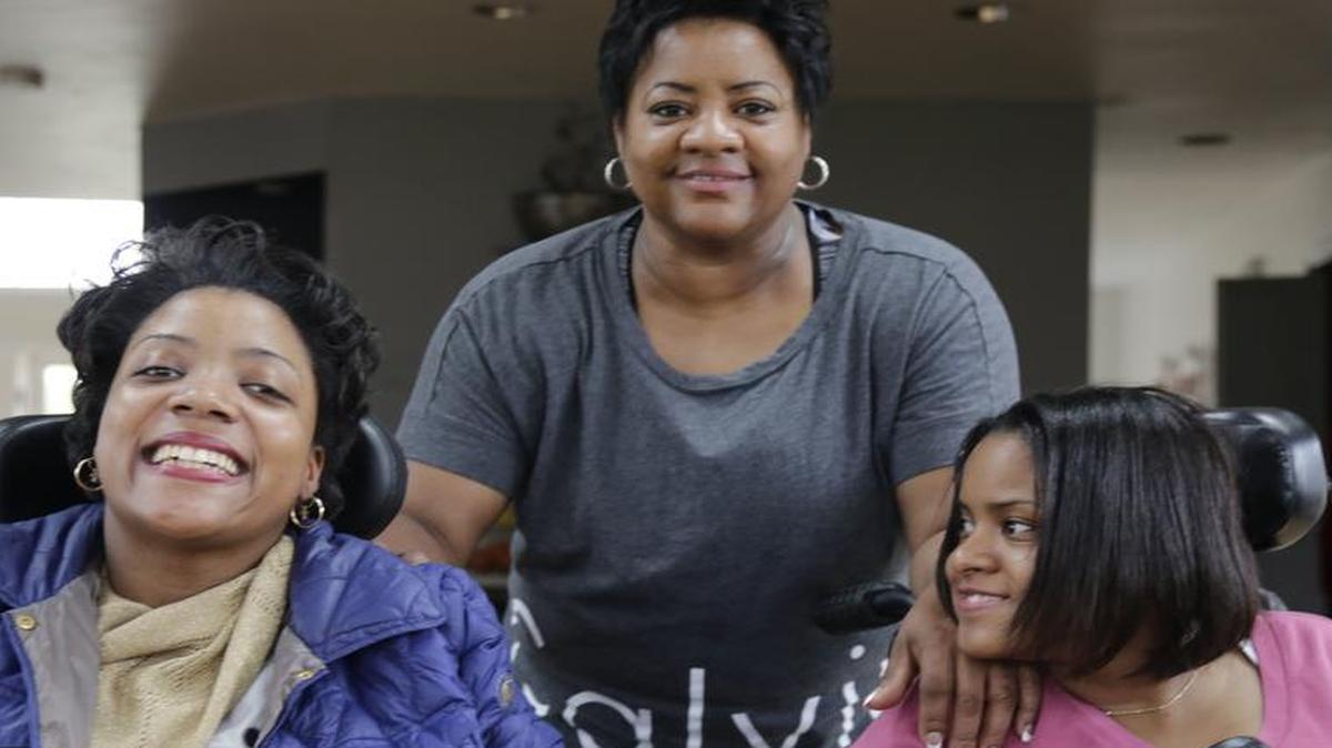 Elaine Walker takes poses with her two daughters Melissa, left, and, Dasia, at their home in South Holland, Ill., on April 28. Illinois Gov. Bruce Rauner is cutting costs in a state budget crisis by limiting overtime worked by home care workers. That would include providers such as Walker,who cares for her daughters, both with cerebral palsy.