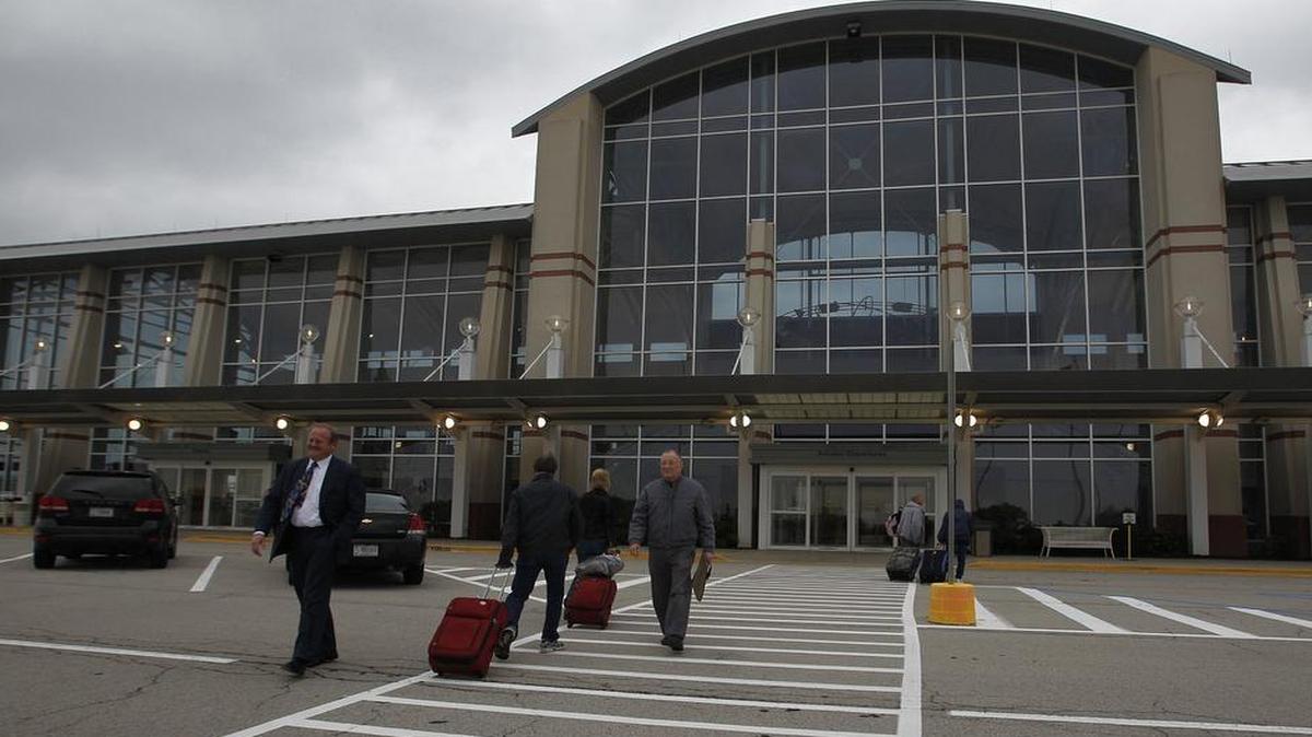 Passengers walk past St. Clair County Chairman Mark Kern, left, as they head into MidAmerica Airport.