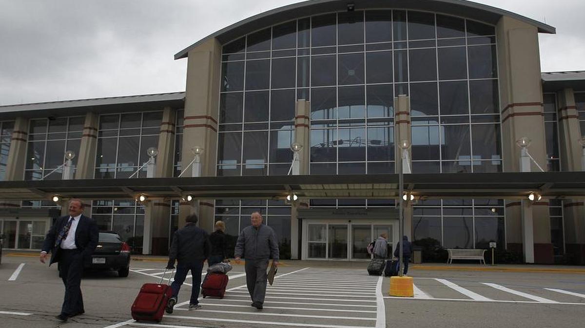 Passengers walk past St. Clair County Chairman Mark Kern as they head into MidAmerica Airport. The County Board doesn’t want responsibility for airport expenses, yet just spent $500,000 on insurance for it.