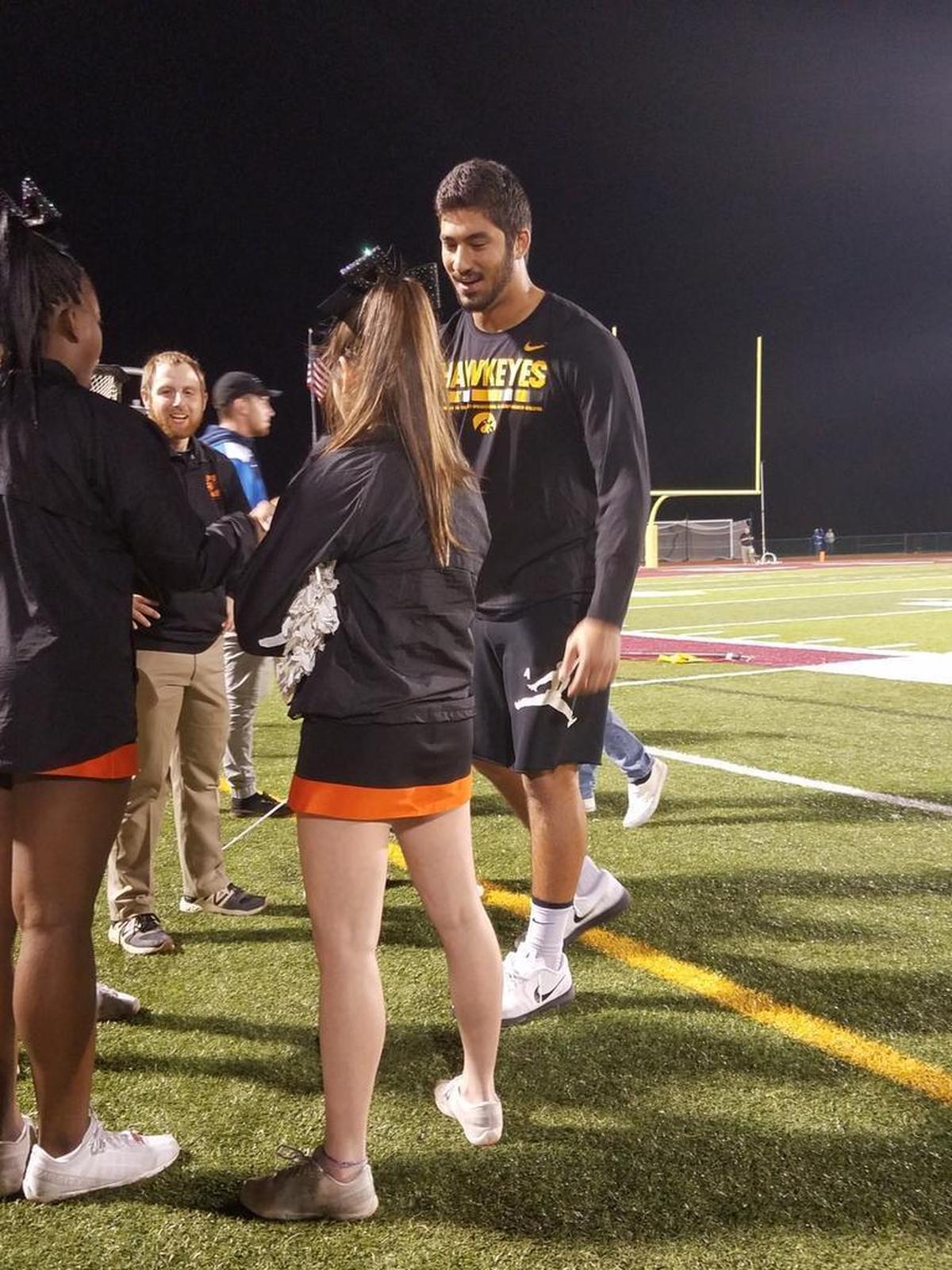 Edwardsville High graduate AJ Epenesa, a freshman football player at the University of Iowa, visits with friends on the cheerleading team Friday during halftime of the Tigers’ game at Belleville West.