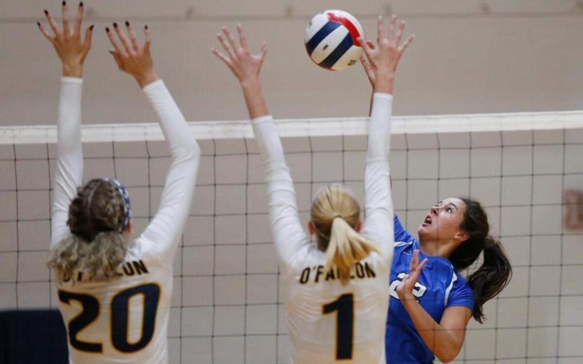 Columbia’s Kelly Metter goes for a kill as O’Fallon’s (20) Cassie Reno and Mackenzie Koester go to block during their game at O’Fallon High School on Monday. The Eagles won the match.