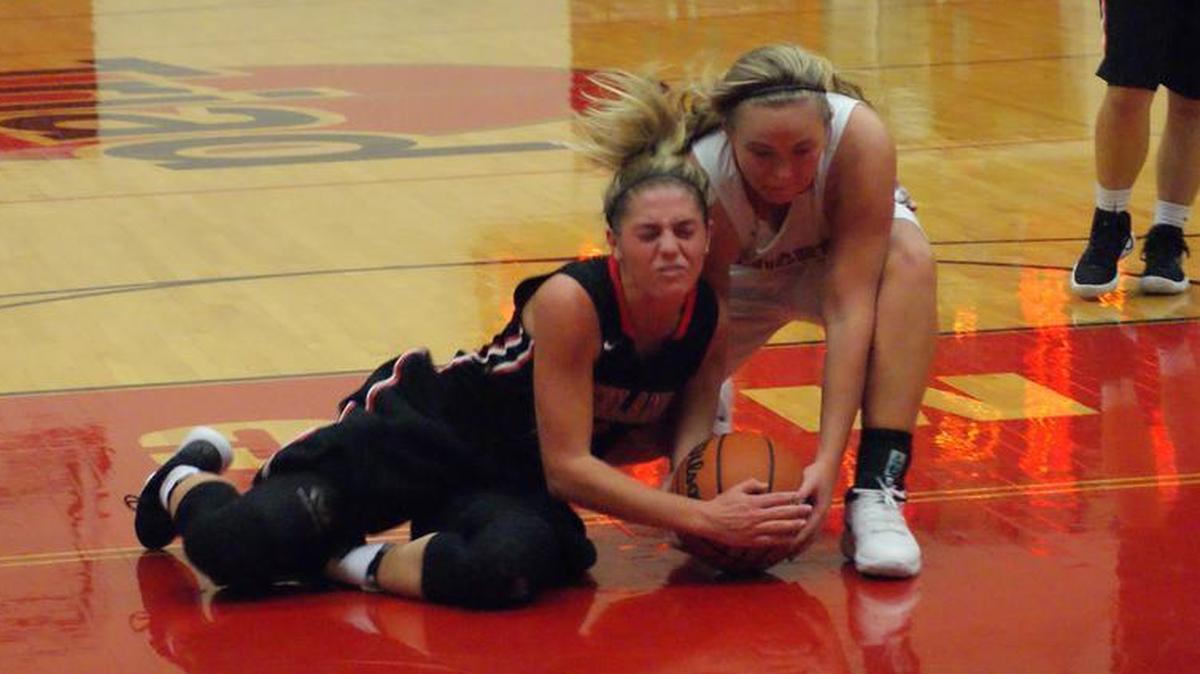 Highland senior Rece Portell, left, wrestles for the ball with Triad senior Brooke Rensburger during the second quarter of the Bulldogs’ 65-30 win over the host Knights Thursday.