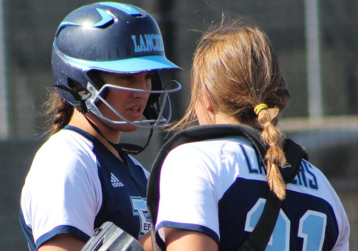 East junior pitcher Kristina Bettis confers with catcher Alex Boze prior to an at-bat during the Lancers’ super-sectional game against Lincoln-Way East at Illinois State University Monday.
