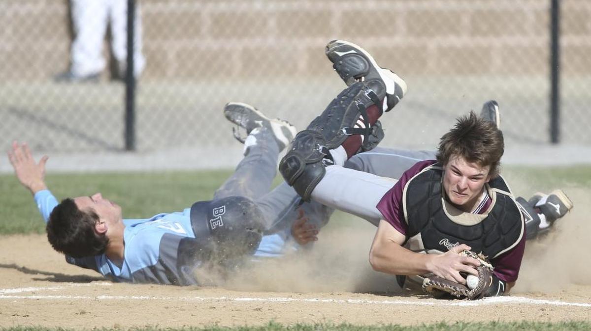 Belleville West catcher Cal Kossina (right) survived a collision with Belleville East’s Patrick Gaul earlier this season and leads the Maroons in hitting.