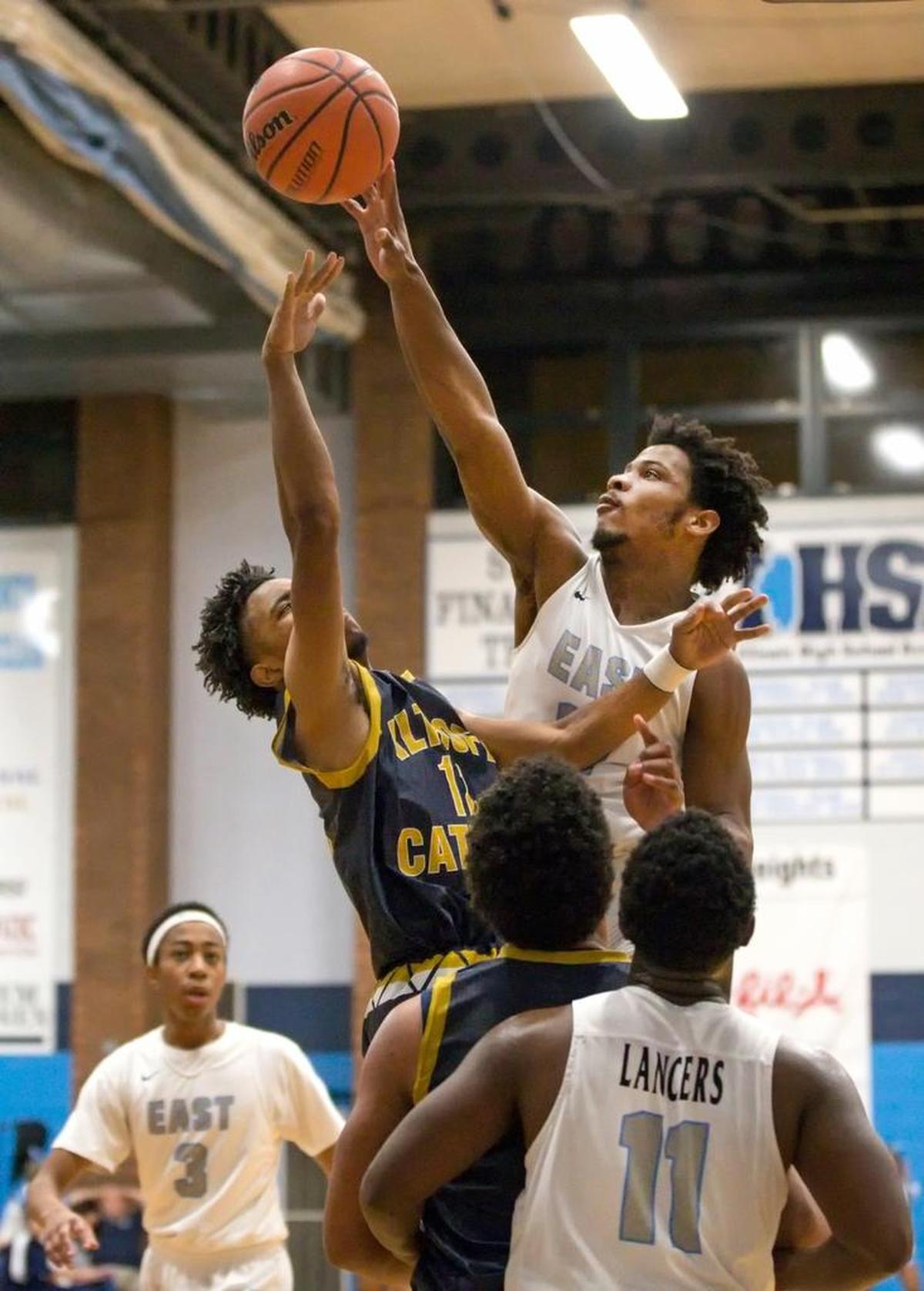 A shot by Althoff’s Ryan McDonald is blocked by Belleville East’s Jordan Yates during Saturday’s Chick-fil-A Classic basketball tournament at Belleville East High School.