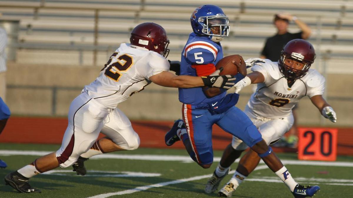 
East St. Louis QB Rayondus Estes is stopped by Montini's Michael Ramos and Nicholas Foster during the first half of their City of Champions Classic game on Saturday.
