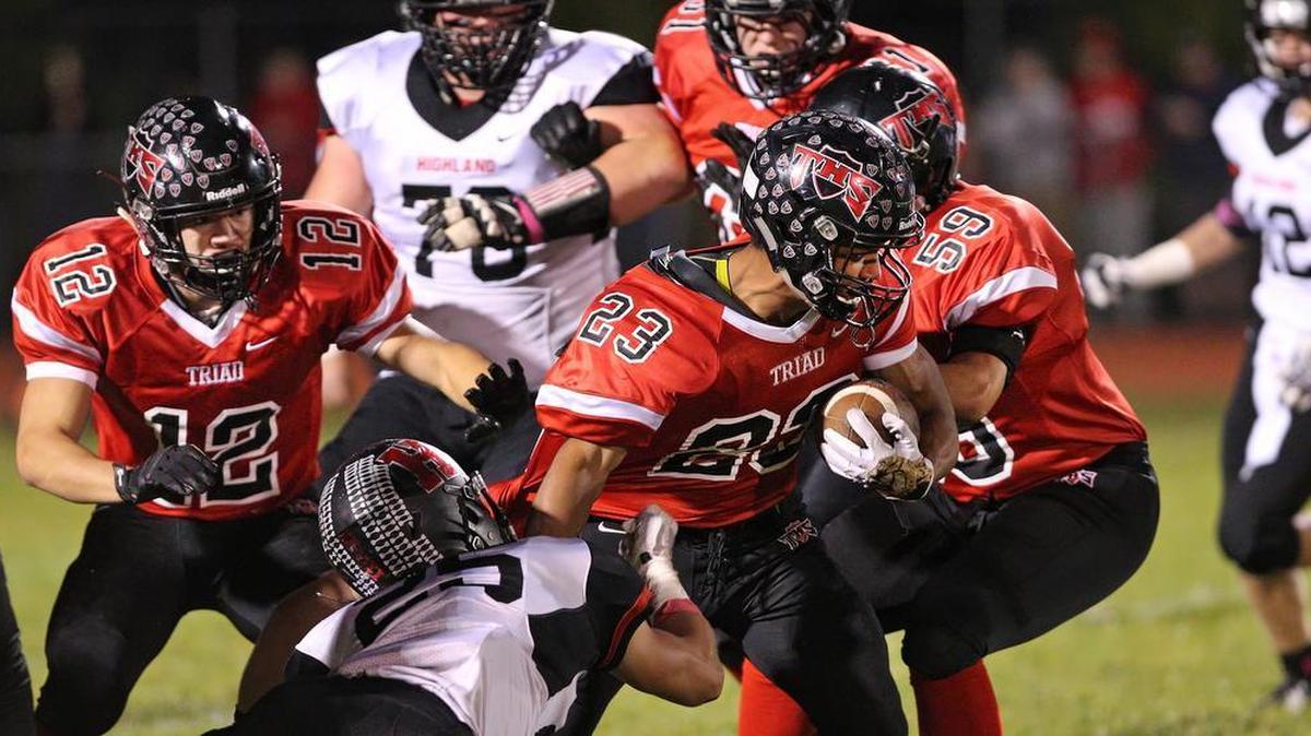
 Triad’s Adam Nelson runs the ball while being grabbed by Highland’s Trent Rakers during Friday’s game at the Triad High School.
