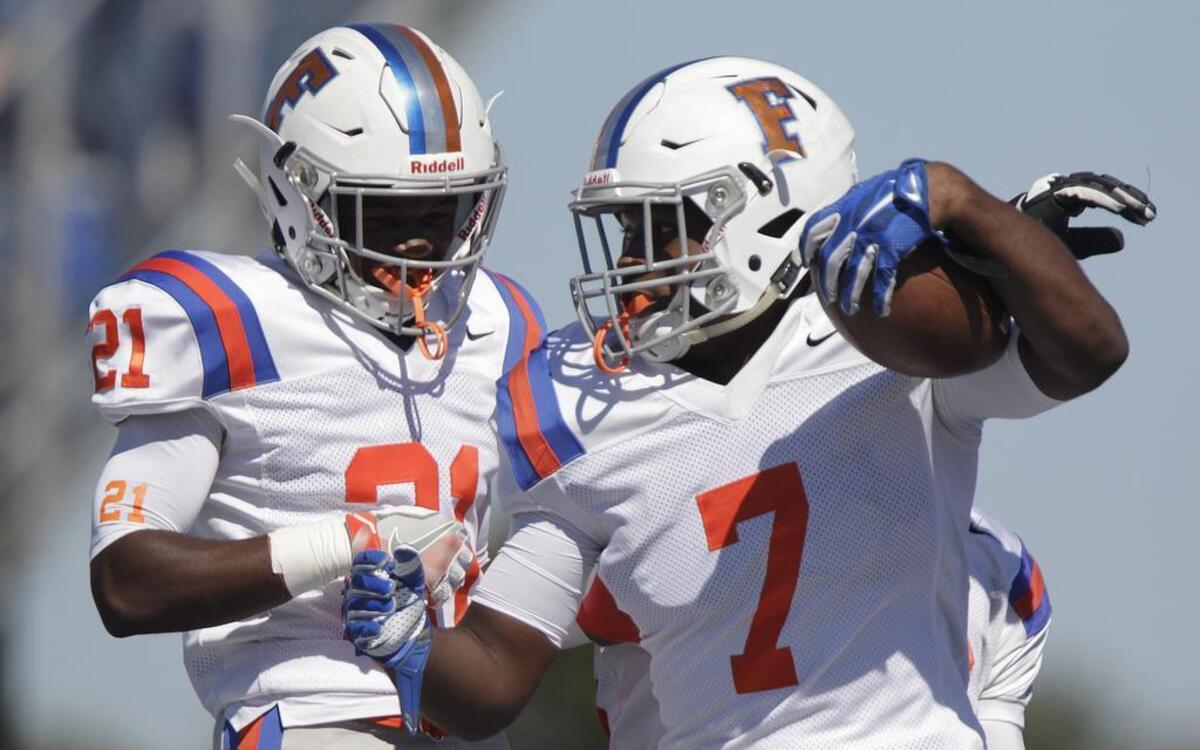 Flyers players Malcolm Bell (21, left) and Ken Dixon (7) celebrate with a jump and bump after Dixon ran in a touchdown in the first quarter.