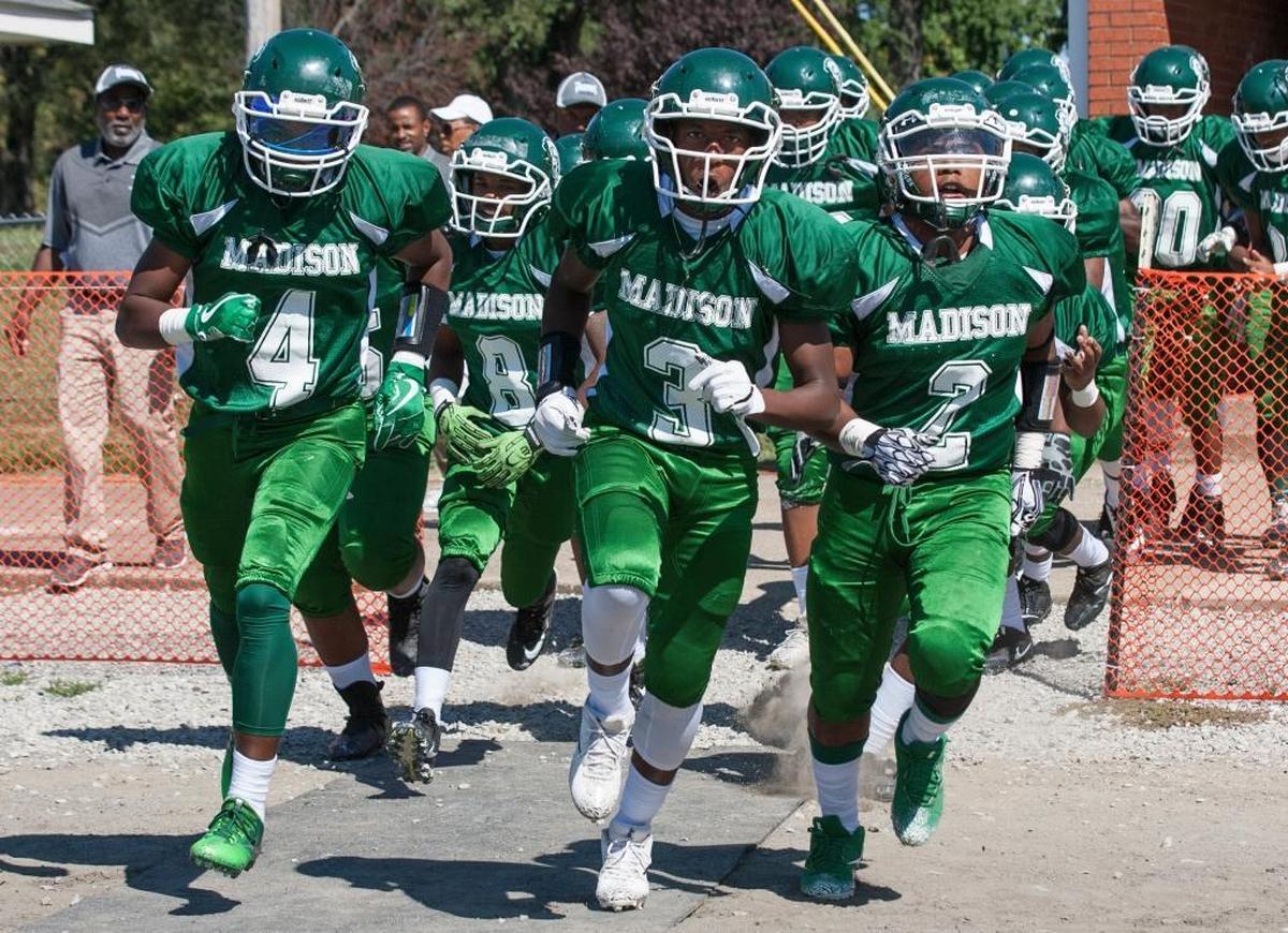 Madison’s Kameron Williams, Carl Moore and Delvondre Jenkins lead Madison onto the field before their game Saturday with Metro East Lutheran.