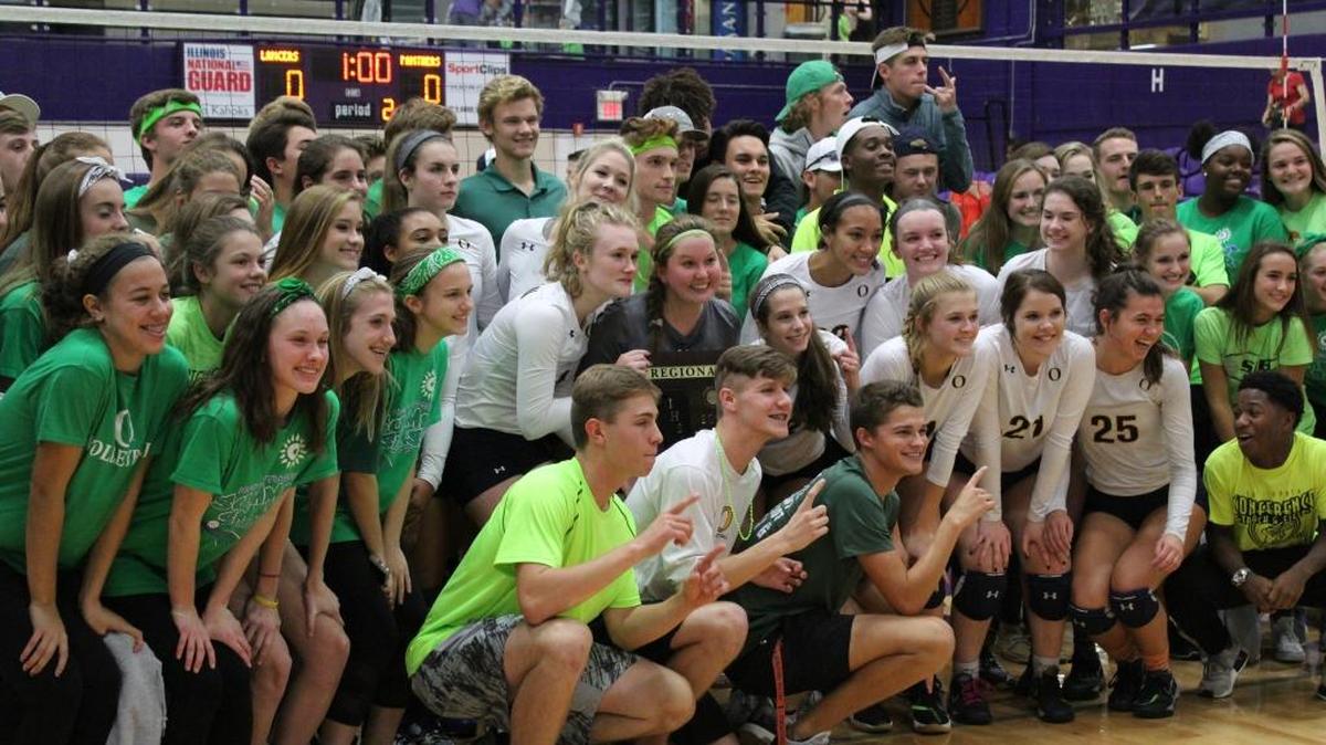 Members of the O’Fallon student cheering section gather around players for a picture with the regional championship placque.