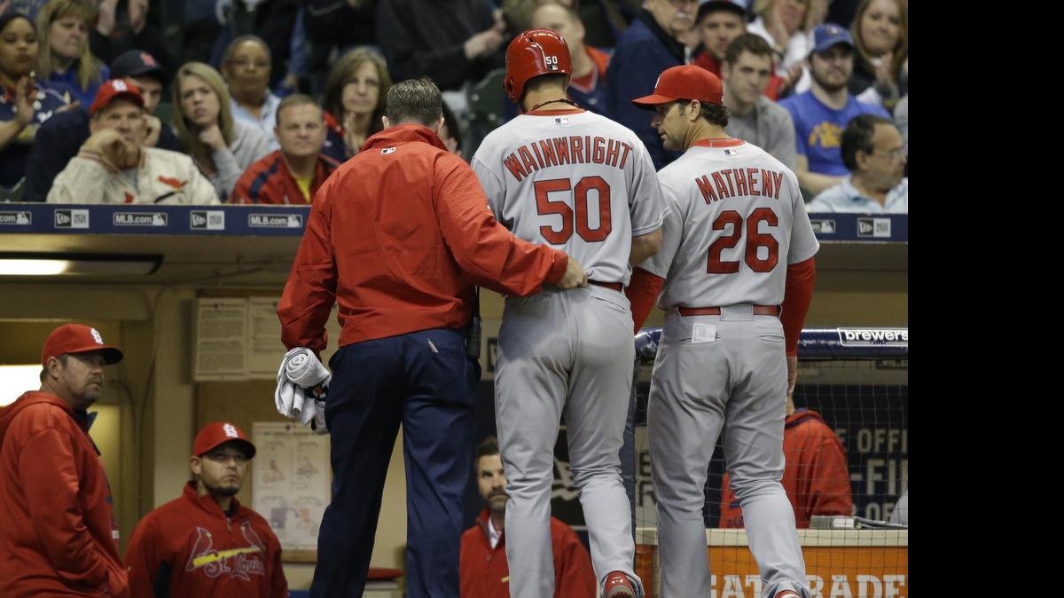 
Cardinals pitcher Adam Wainwright is helped off the field after getting injured while batting during the fifth inning Saturday against the Brewers in Milwaukee. The Cardinals defeated the Brewers 5-3.
