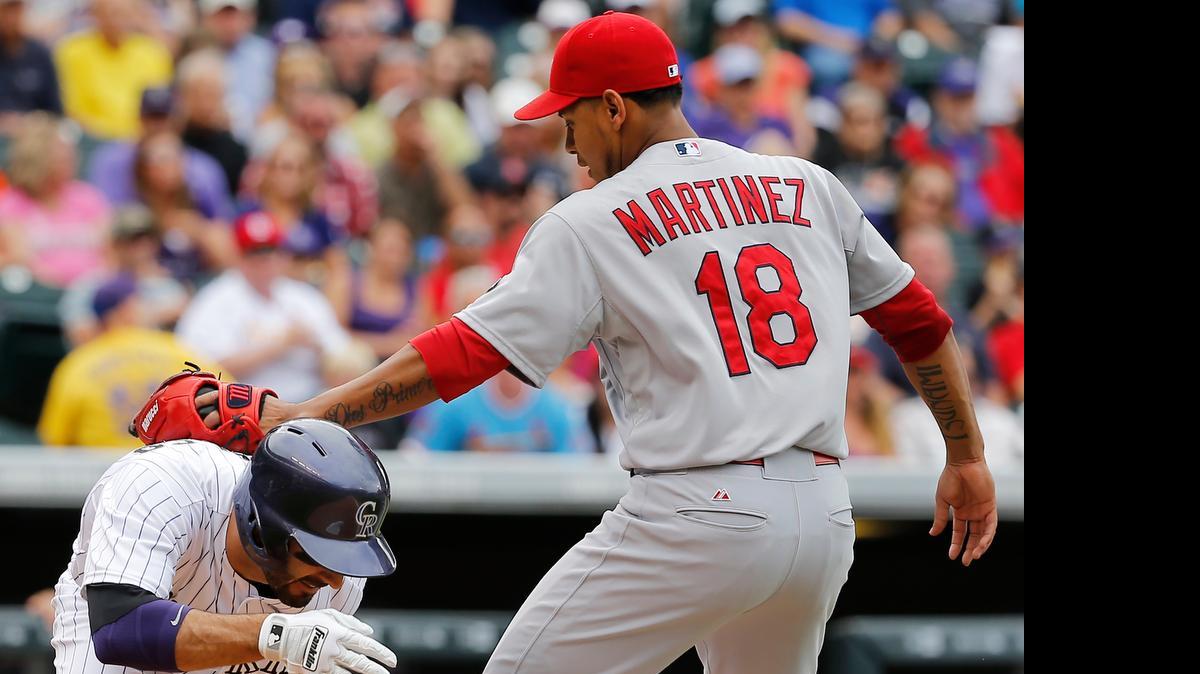 
The Cardinals’ Carlos Martinez tags out the Rockies’ Daniel Descalso during the fourth inning Wednesday in Denver. The Cardinals won 4-2, after dropping the first two games in the three-game series.
