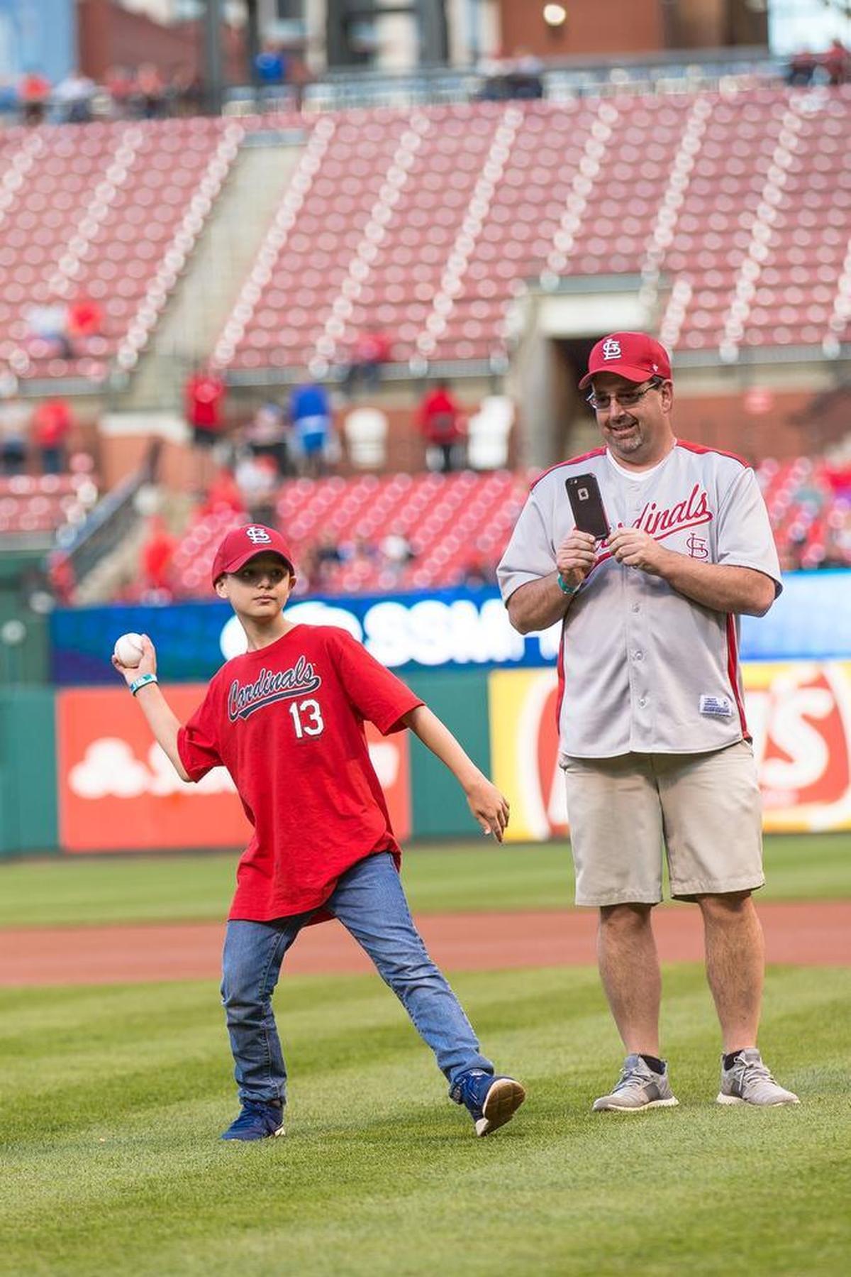 Jackson Cruthis throws out a ceremonial first pitch before the St. Louis Cardinals and Milwaukee Brewers game at Busch Stadium Monday, May 1. Capturing the moment on his iPhone is his dad, Chad Cruthis, the athletic director and girls basketball coach at Lebanon High School.