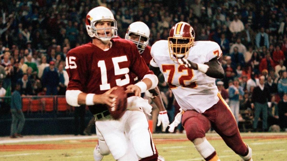 St. Louis Cardinals quarterback Neil Lomax, 15, is chased by Redskins Dexter Manley, 72, during NFL action at RFK Memorial Stadium in Washington on Monday, Oct. 7, 1985.