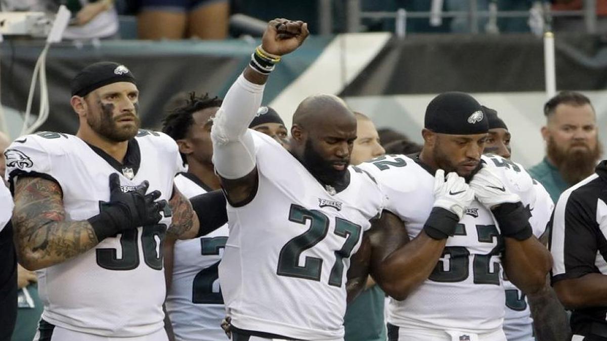 Chris Long, 56, holds one hand over his heart and another on the shoulder of teammate Malcolm Jenkins, whose thrust his fist in the air in protest of racial injustice.