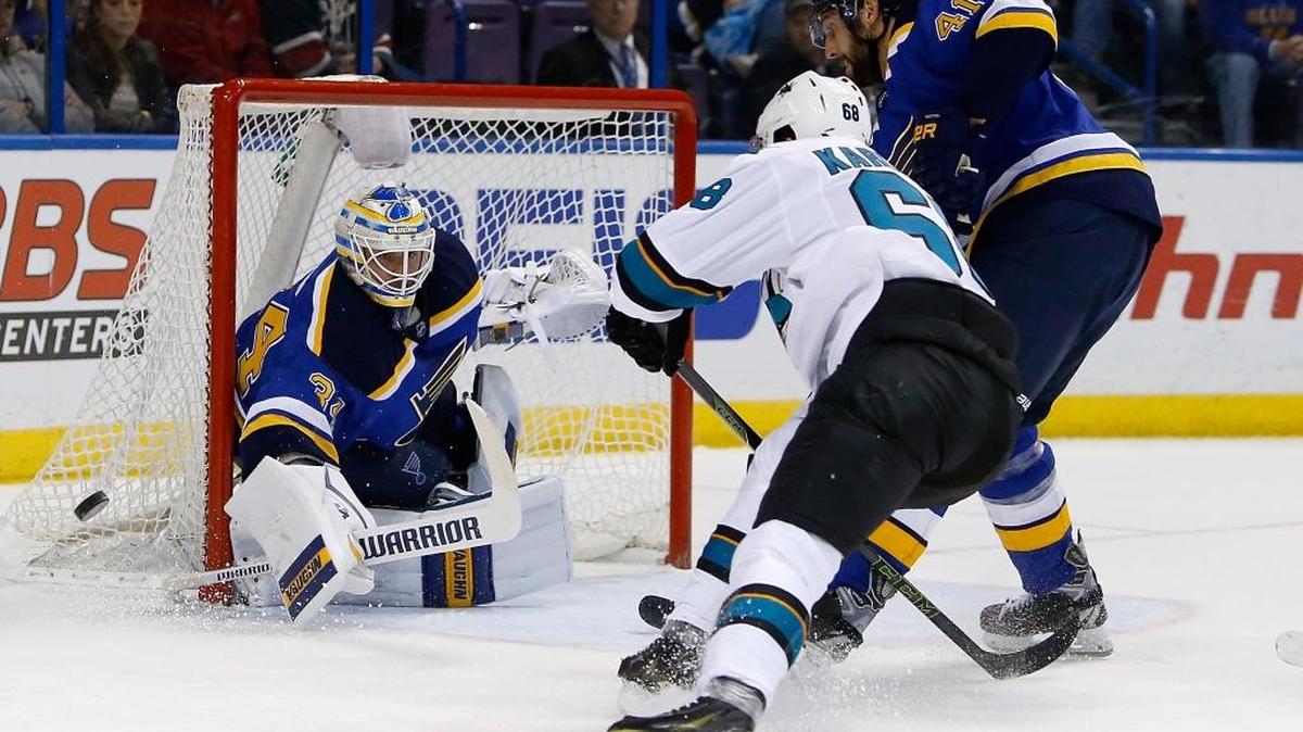 =Blues goalie Jake Allen, left, deflects a shot on goal from San Jose Sharks' Melker Karlsson, center during the first period Feb. 22 in St. Louis. (AP Photo/Scott Kane)