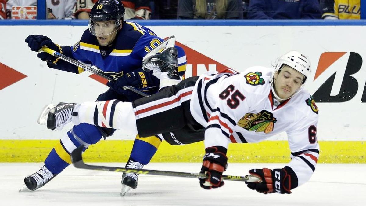 The Chicago Blackhawks’ Andrew Shaw, right, is sent flying after colliding with St. Louis Blues’ Scottie Upshall while reaching for a puck Monday in St. Louis.