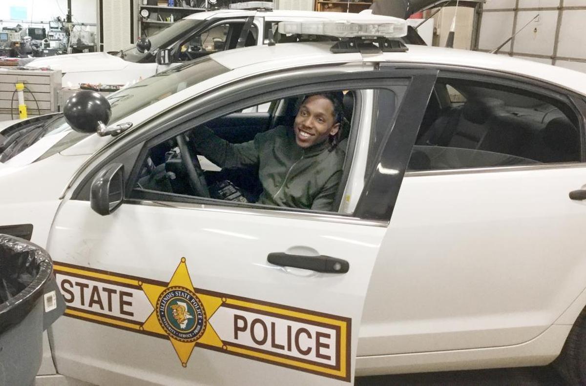 Tennessee Titans star cornerback and kick returner Adoree Jackson, a Belleville native, takes a seat in a squad car Friday at Illinois State Police Headquarters in Collinsville.